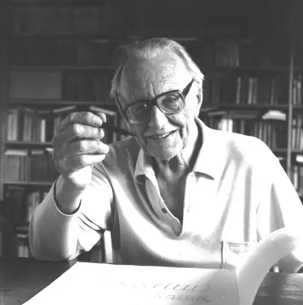 Carl Orff mit der Pfeiffe in der Hand schlägt eine Notenskizze auf